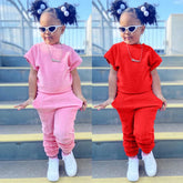 A young girl models a two-piece cotton set featuring a short-sleeve t-shirt and matching pants.
