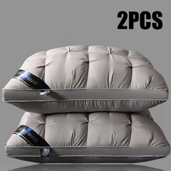 Two grey tufted bed pillows stacked on top of each other against a plain background.