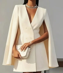 A woman wears a white double-breasted mini dress with a V-neck and cape sleeves.