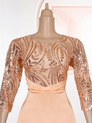 A peach-colored floor-length dress featuring a sequined bodice with long sleeves and a fitted waist.