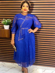 A woman wears a royal blue midi dress featuring sheer lace sleeves and a decorative beaded sash.