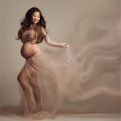 A pregnant woman wears a long-sleeved lace top and a flowing tulle skirt for a photoshoot.