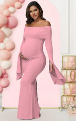 A pregnant woman wears a solid pink off-shoulder mermaid dress with long flared sleeves.