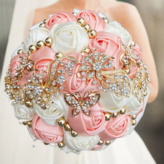 A round wedding bouquet of pink and white silk roses accented with gold beads and crystal brooches.