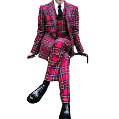 A man wears a three-piece red plaid suit with a white shirt and black tie.