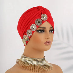 A red pleated turban cap decorated with a row of circular rhinestone embellishments.