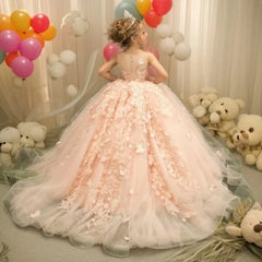 A girl wears a floor-length pink tulle ball gown with floral lace appliques and a sheer back.