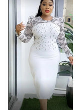 A woman wears a white midi dress with black lace sleeves and a beaded bodice.