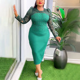 A woman wears a green midi-length sheath dress with long sheer sleeves and diamond bead detailing.