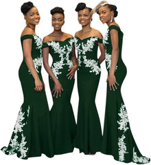 Four women wear matching dark green off-the-shoulder mermaid dresses with white floral appliques.