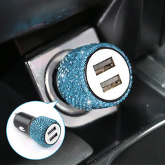 A dual USB car charger decorated with blue rhinestones plugged into a vehicle power outlet.
