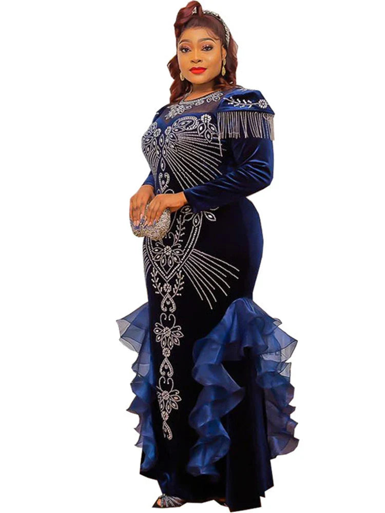 A woman wears a long-sleeved navy blue velvet mermaid gown with crystal embellishments and ruffles.