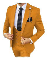 A man wears a mustard yellow three-piece slim fit suit with a white shirt and polka dot tie.