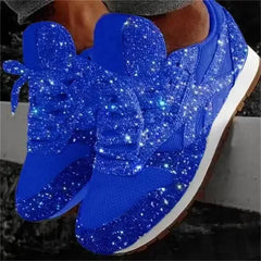 A pair of bright blue lace-up sneakers covered in sparkling glitter with a white platform sole.