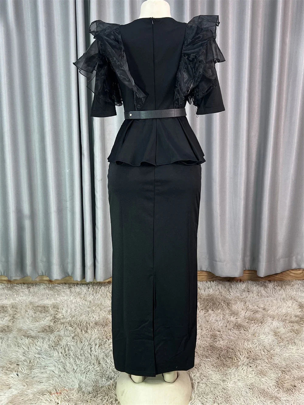 A black ankle-length dress with ruffled sleeves, a peplum waist, and a back zipper closure.