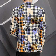 A man wears a slim-fit blazer featuring a colorful plaid and leaf-patterned print.