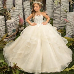 A girl wears a light champagne ball gown with floral appliques and a tiered tulle skirt.