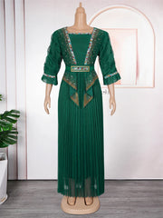 A floor-length emerald green pleated dress with embellished trim and a matching waist belt.