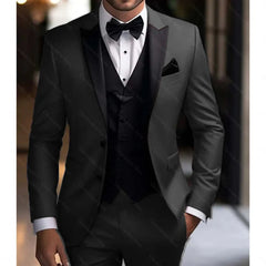 A man wears a charcoal grey three-piece tuxedo with a black peak lapel, vest, and bow tie.