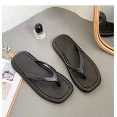 A pair of minimalist black flip-flops with a square-toe design and flat soles.