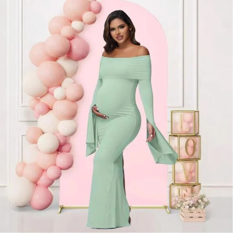 A pregnant woman wears a sage green off-shoulder mermaid dress with long flared sleeves.