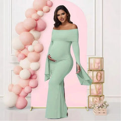 A pregnant woman wears a sage green off-shoulder mermaid dress with long flared sleeves.