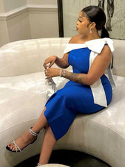 A woman wears a royal blue, mid-calf, sleeveless dress featuring a white bow detail on the shoulder.