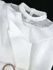 A white knee-length dress featuring a beaded mesh neckline and structured ruffled peplum detail.
