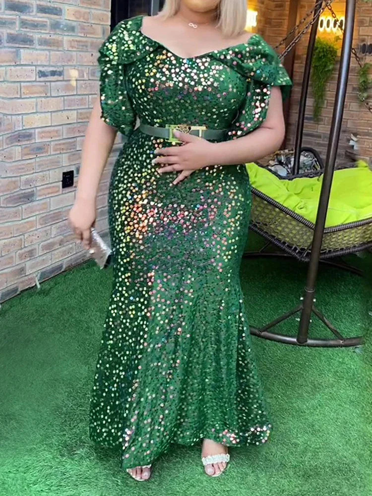 A woman wears a floor-length, emerald green sequined mermaid dress with petal sleeves.