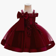 A sleeveless burgundy knee-length ball gown for girls featuring a large bow and floral embroidery.