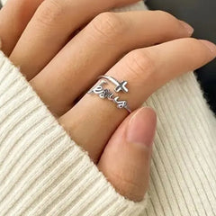 A silver-colored ring featuring the word Jesus in cursive script and a small cross accent.
