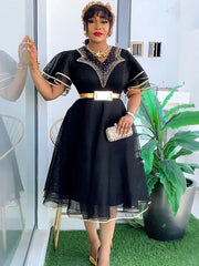 A woman wears a black knee-length dress with ruffled sleeves, a gold belt, and beaded neckline.