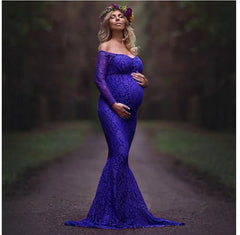 A pregnant woman wears a long-sleeved, off-shoulder royal blue lace mermaid maternity gown.