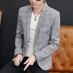 A man wears a grey plaid single-button blazer over a white t-shirt.