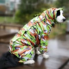 A dog wearing a green, orange, and white camouflage-patterned hooded raincoat.