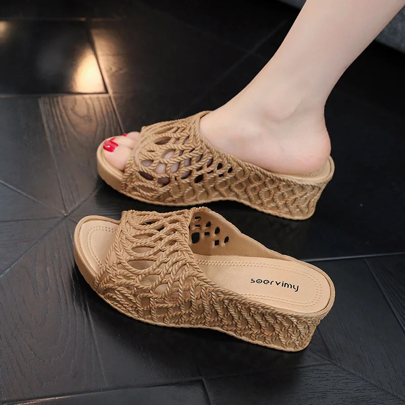 A pair of apricot-colored wedge slippers with a hollow-out braided design and peep-toe front.