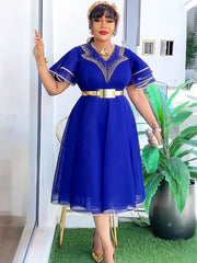 A woman wears a royal blue midi dress with ruffle sleeves, a gold belt, and beaded neckline detail.