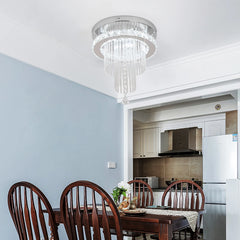 A modern crystal raindrop chandelier with a polished chrome finish mounted on a dining room ceiling.
