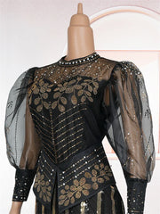 A black floor-length evening gown with gold sequin floral patterns and sheer puff sleeves.