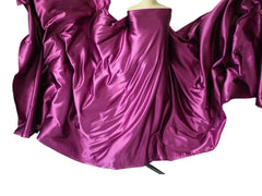 A vibrant magenta satin fabric draped over a mannequin to create a flowing, wavy effect.