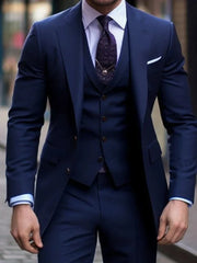 A man wears a slim-fit navy blue three-piece suit with a notched lapel and a patterned tie.