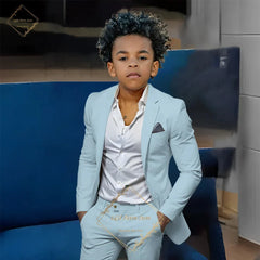 A young boy wearing a light blue slim-fit suit with a white button-down shirt.