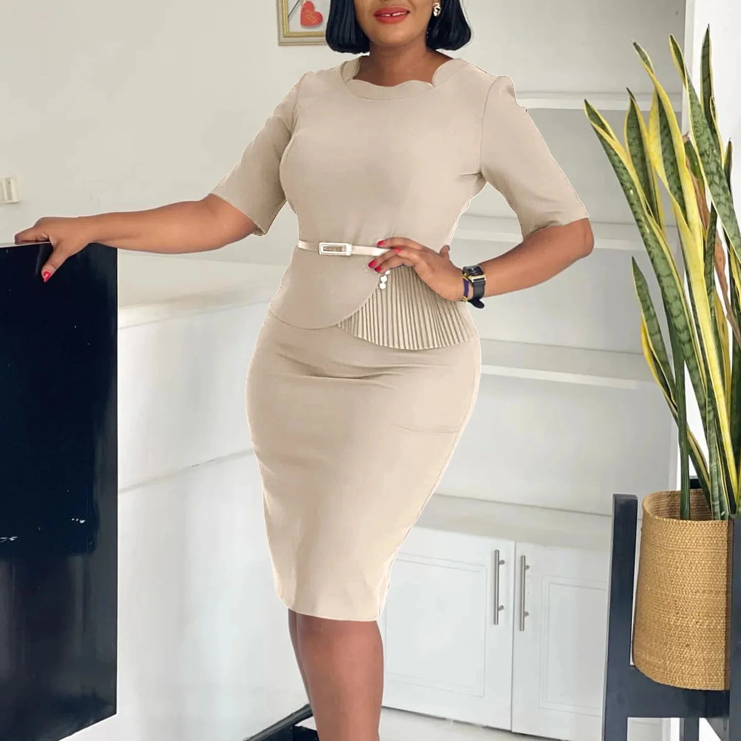 A woman wears a beige midi sheath dress with a square neckline, half sleeves, and a belted waist.