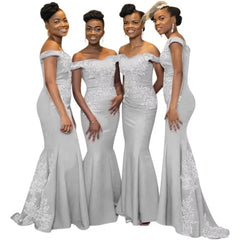 Four women wear matching floor-length grey satin mermaid bridesmaid dresses with lace appliques.