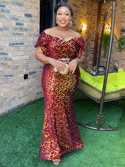 A woman wears a floor-length, off-the-shoulder burgundy sequin mermaid gown with petal sleeves.