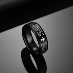 A black stainless steel ring engraved with the Lord's Prayer and a white cross symbol.