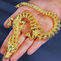 A golden articulated dragon figurine with movable limbs resting in a person's palm.