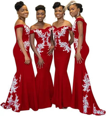 Four women wear matching burgundy off-the-shoulder mermaid dresses with white floral lace appliques.