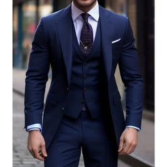 A man wears a slim-fit navy blue three-piece suit with a notched lapel and a textured tie.