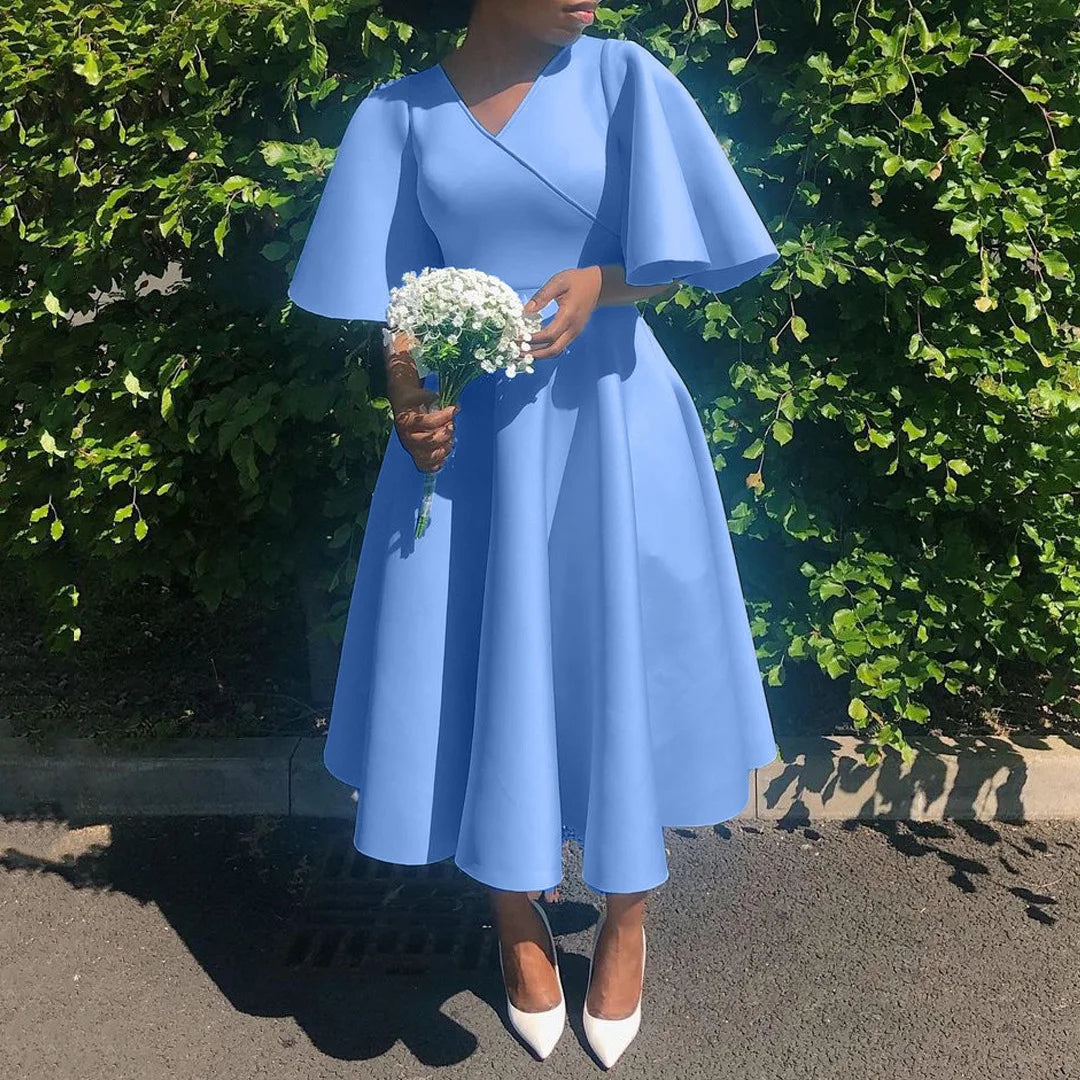 A woman wears a light blue V-neck midi dress with butterfly sleeves and a pleated A-line skirt.